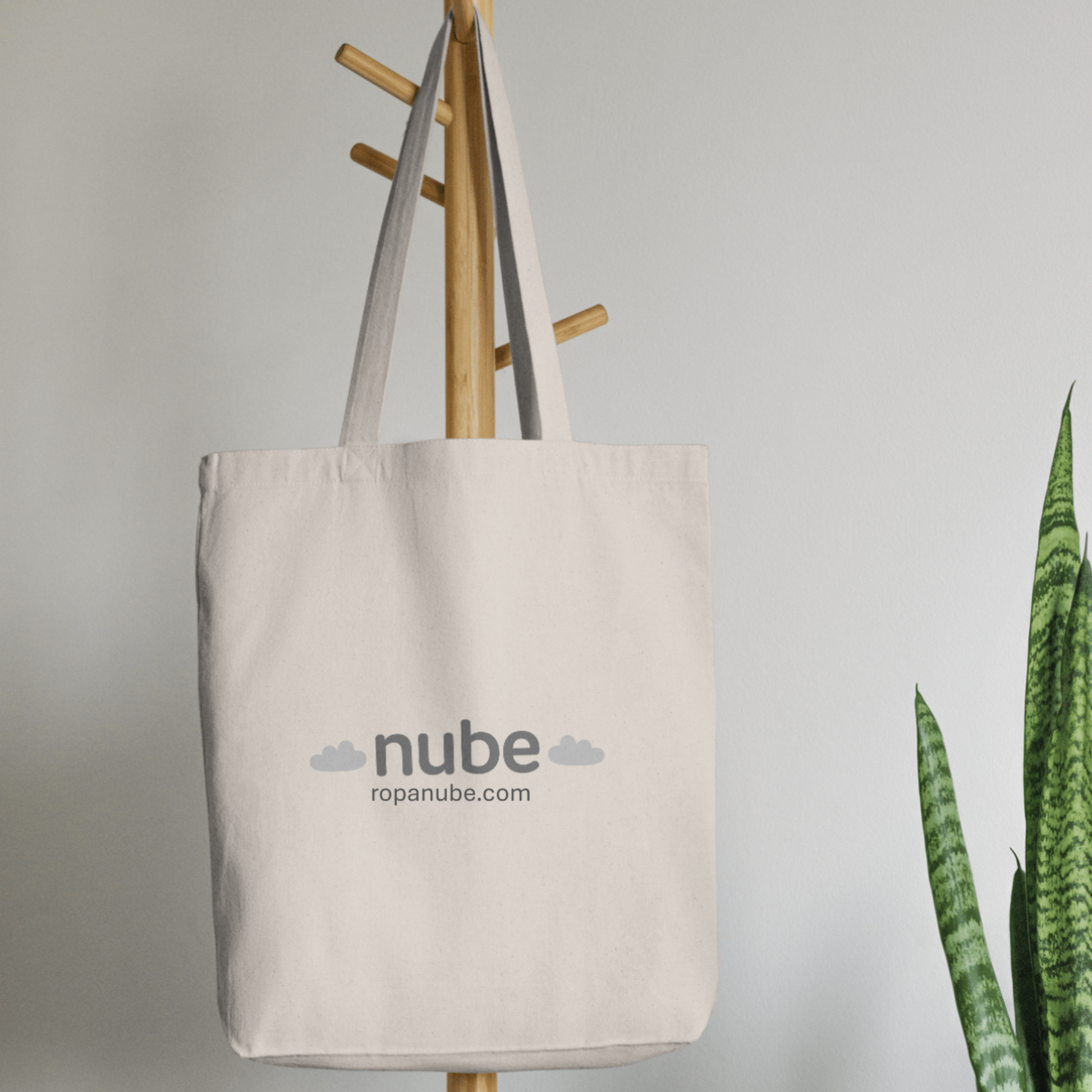 Bolsa Tote Bag en color beige con estampado marca ropa Nube colgado en perchero madera 