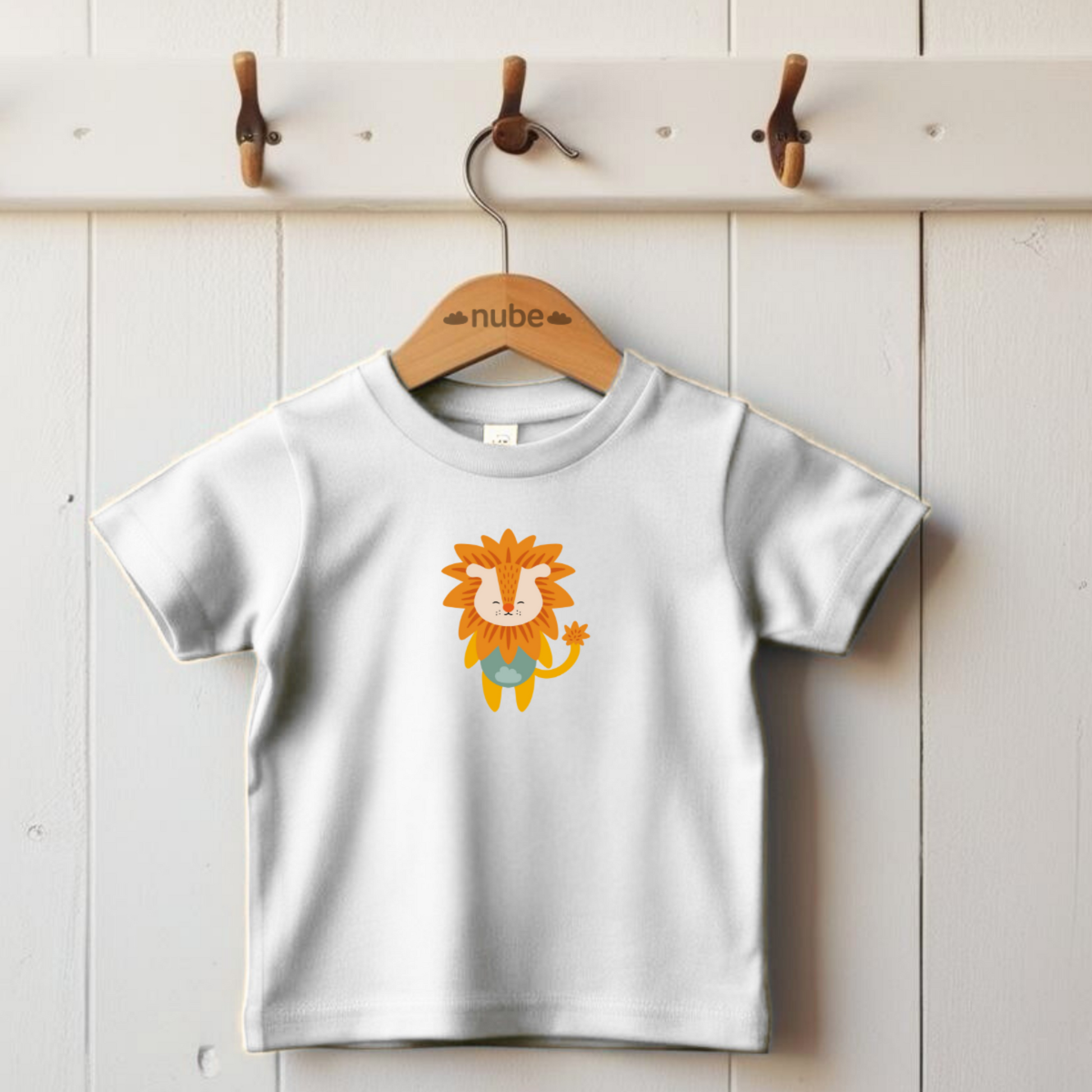 Playera blanca colgada en un gancho con diseño del león de la marca nube de pie con melena naranja y ropa verde