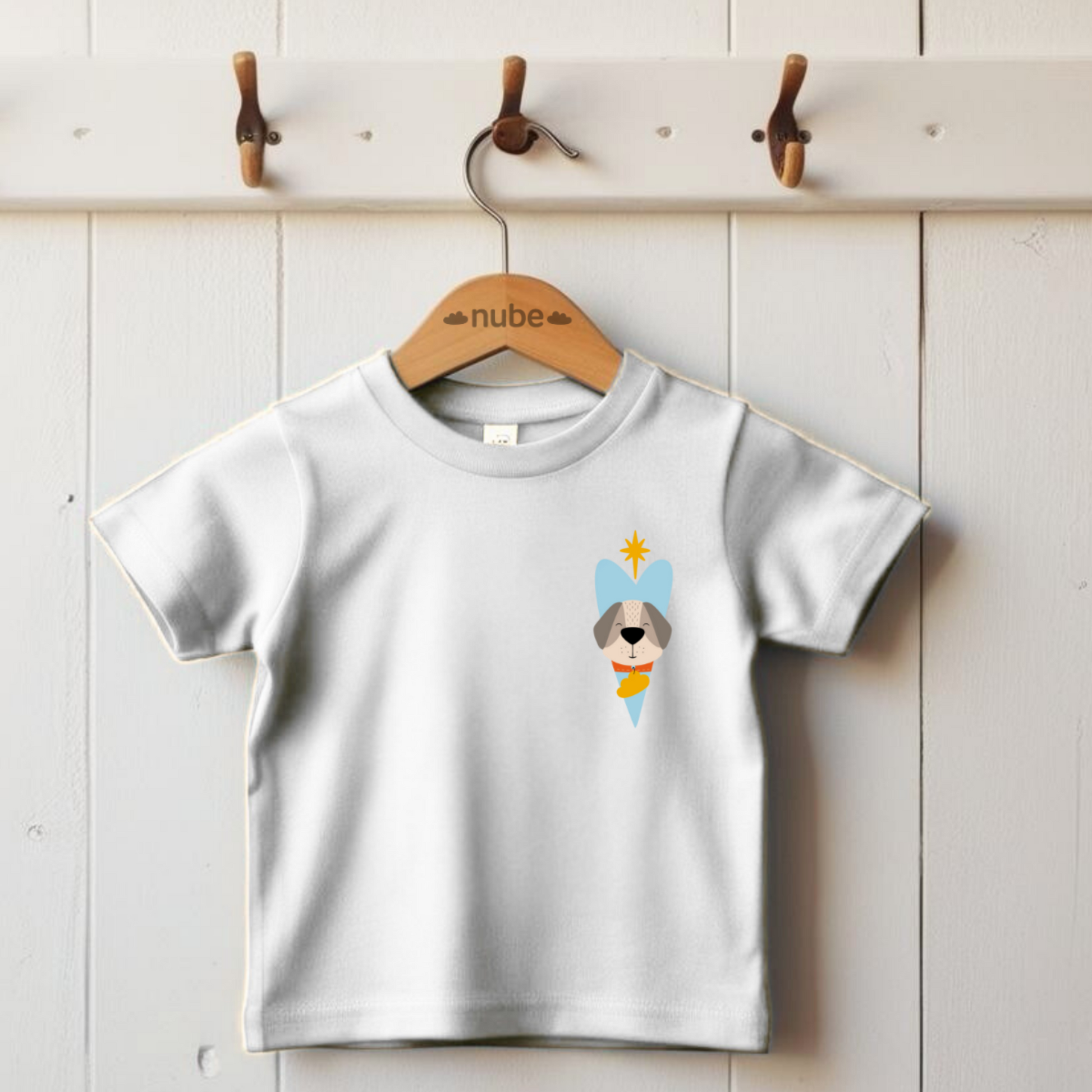 Playera blanca colgada en un gancho con diseño del perro  Leandro de la marca nube dentro de un corazón azul y una estrella amarilla en la parte superior lo guía