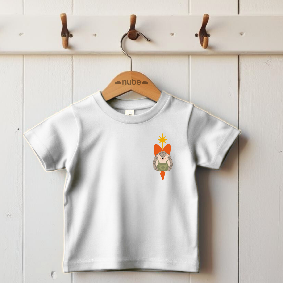 Playera blanca colgada en un gancho con diseño de un puercoespín dentro de un corazón naranja y una estrella amarilla en la parte superior del pecho.