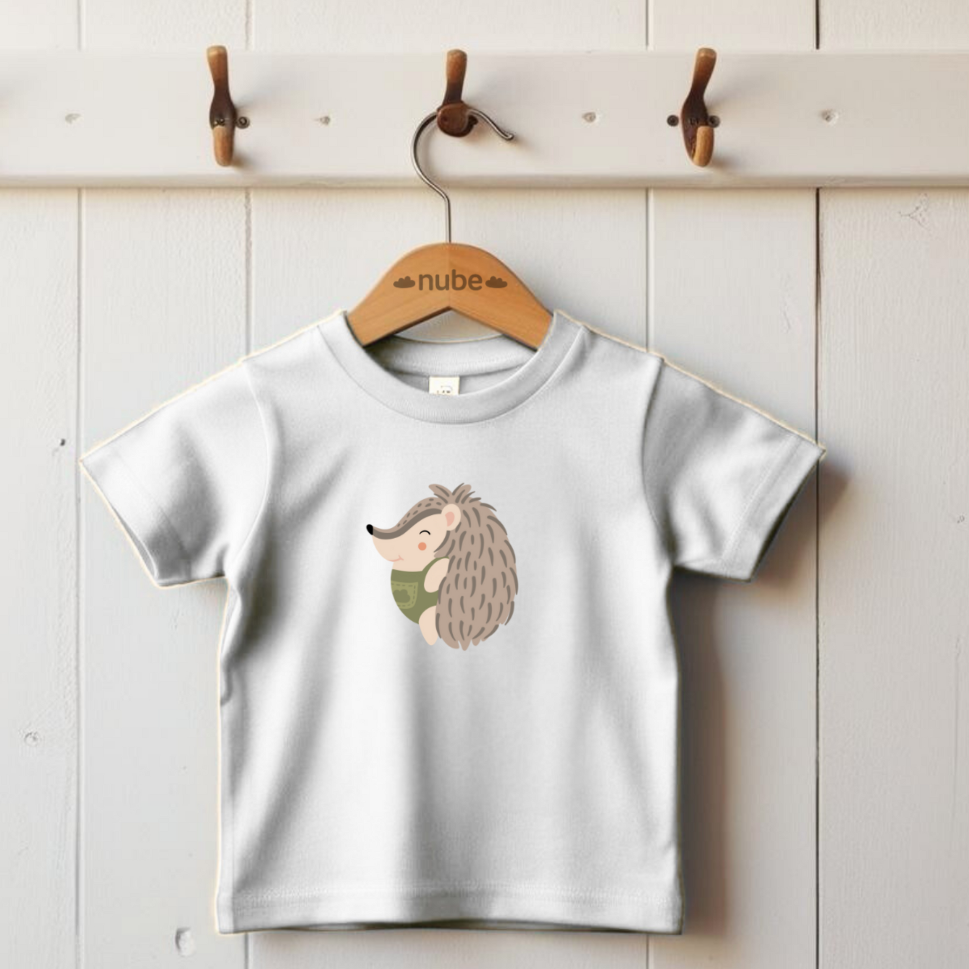 Playera blanca colgada en gancho con el estampado del puercoespin Filomeno de la marca de ropa nube de perfil con traje verde con dibujo de nube