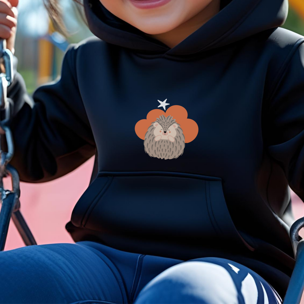 Toddler jugando en el parque con sudadera tipo hoodie negra con diseño de Filomena el Puercoespín de la marca de ropa Nube dentro de una nube naranja y una estrella blanca a lado.