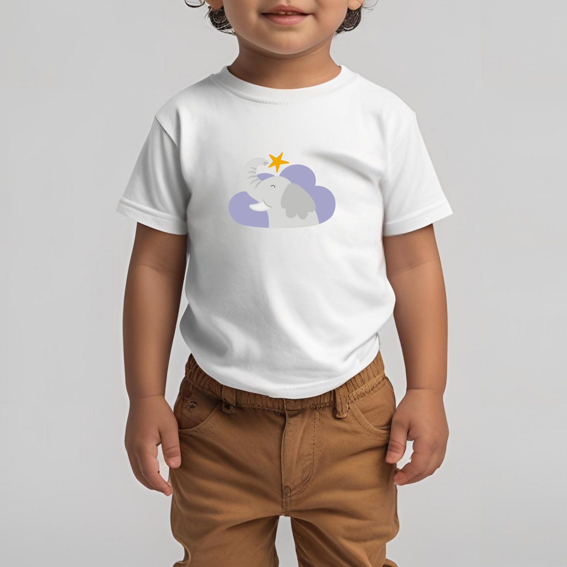 Toddler con pantalones cafés y playera blanca con estampado del elefante Clementino de la marca de ropa nube dentro de un corazón morado. Arriba los guía una estrella amarilla.