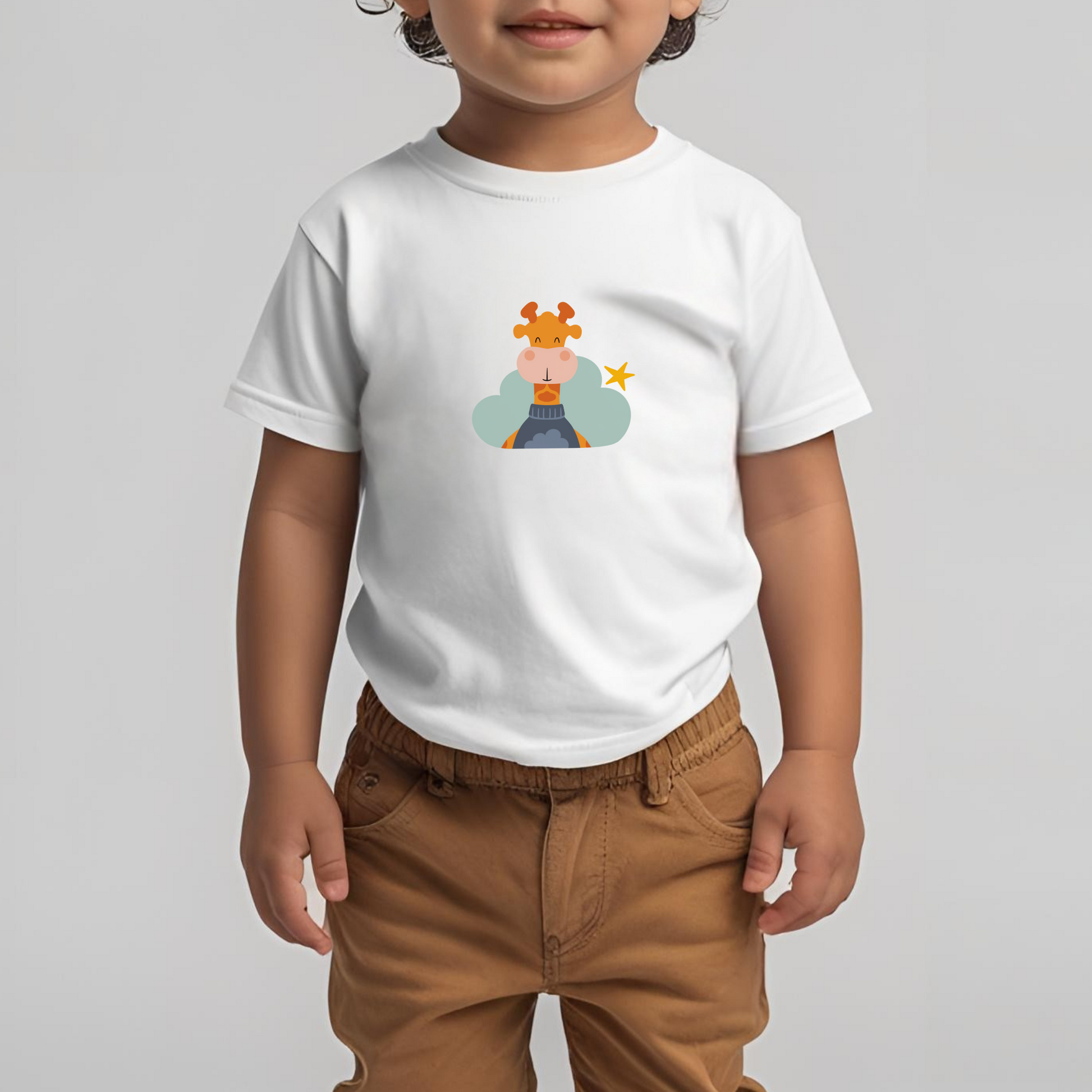 Toddler con pantalón café y playera blanca de la marca de ropa nube con estampado de la jirafa Lazaro en una Nube color verde y una estrella amarilla colgada en el respaldo del sillón.