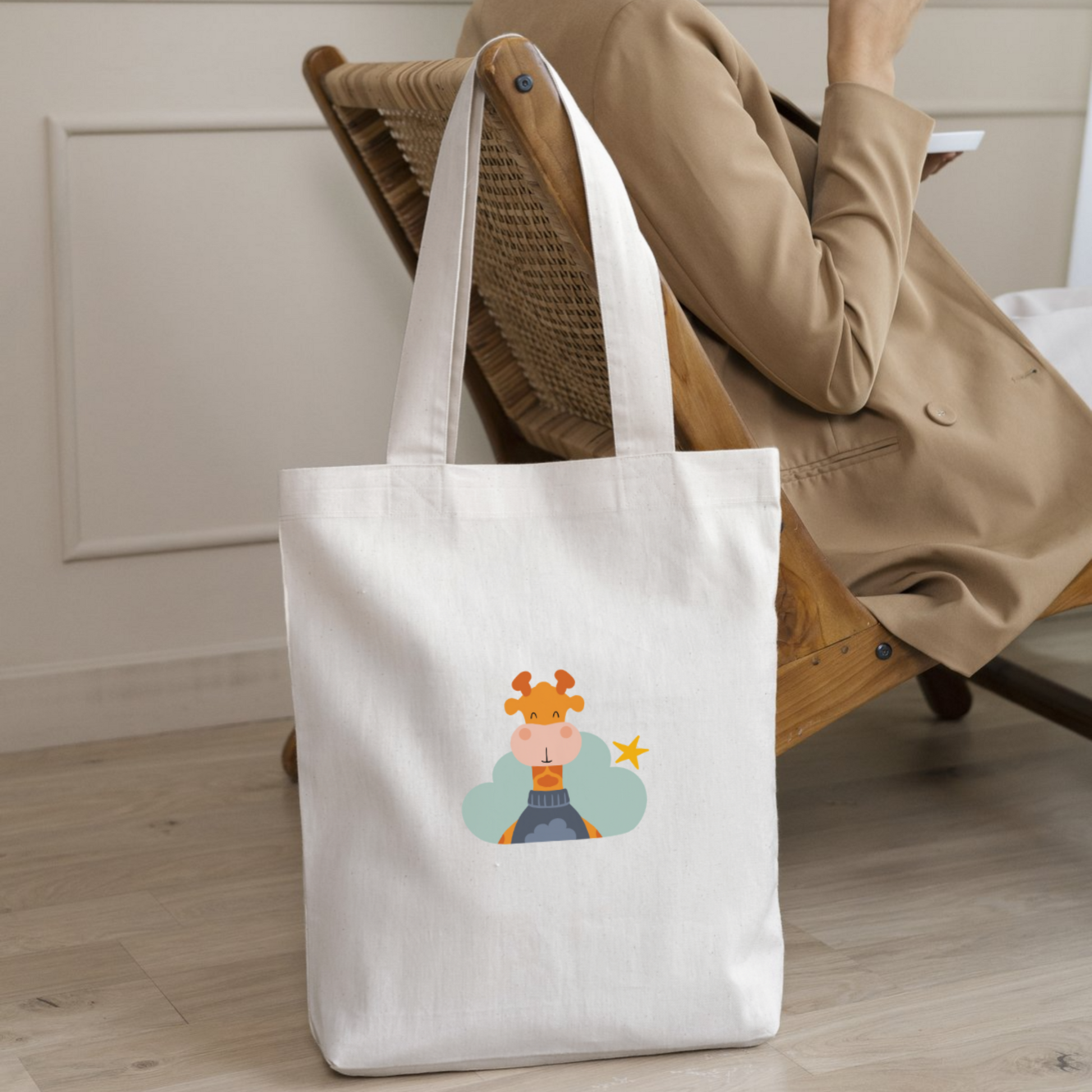 Mujer con saco con la bolsa tote bag de la marca de ropa nube con estampado de la jirafa Lazaro en una Nube color verde y una estrella amarilla colgada en el respaldo del sillón.
