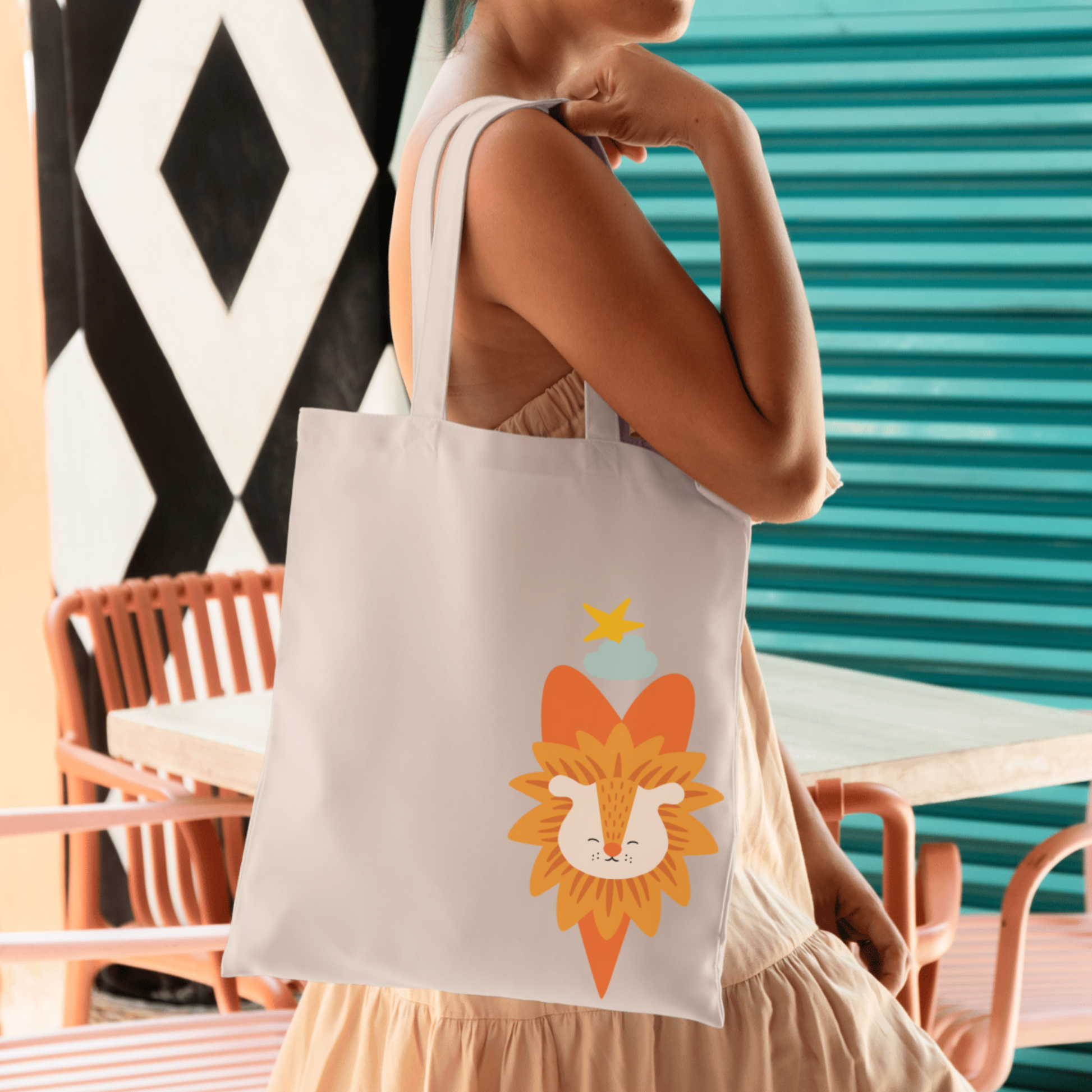 Mujer con vestido ligero sostiene la tote bag de la marca de ropa nube con estampado del león Sabino con un traje verde de la marca de ropa nube dentro de un corazón naranja. Arriba lo guía una estrella amarilla y una nube azul.