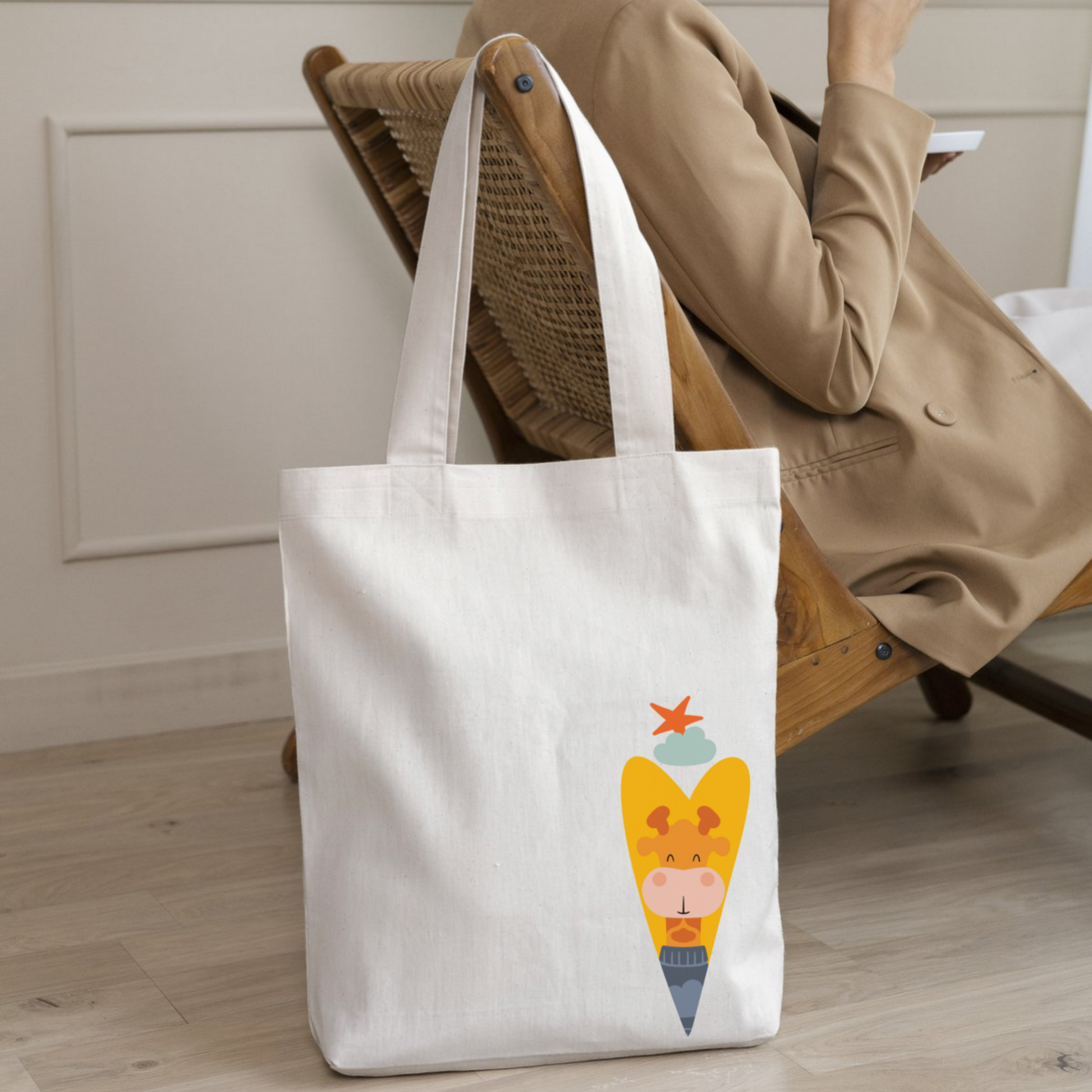 Mujer con saco con tote bag de la marca de ropa nube con estampado de la jirafa Lazaro dentro de un corazón amarillo. Arriba los guía una estrella naranja y una nube azul.