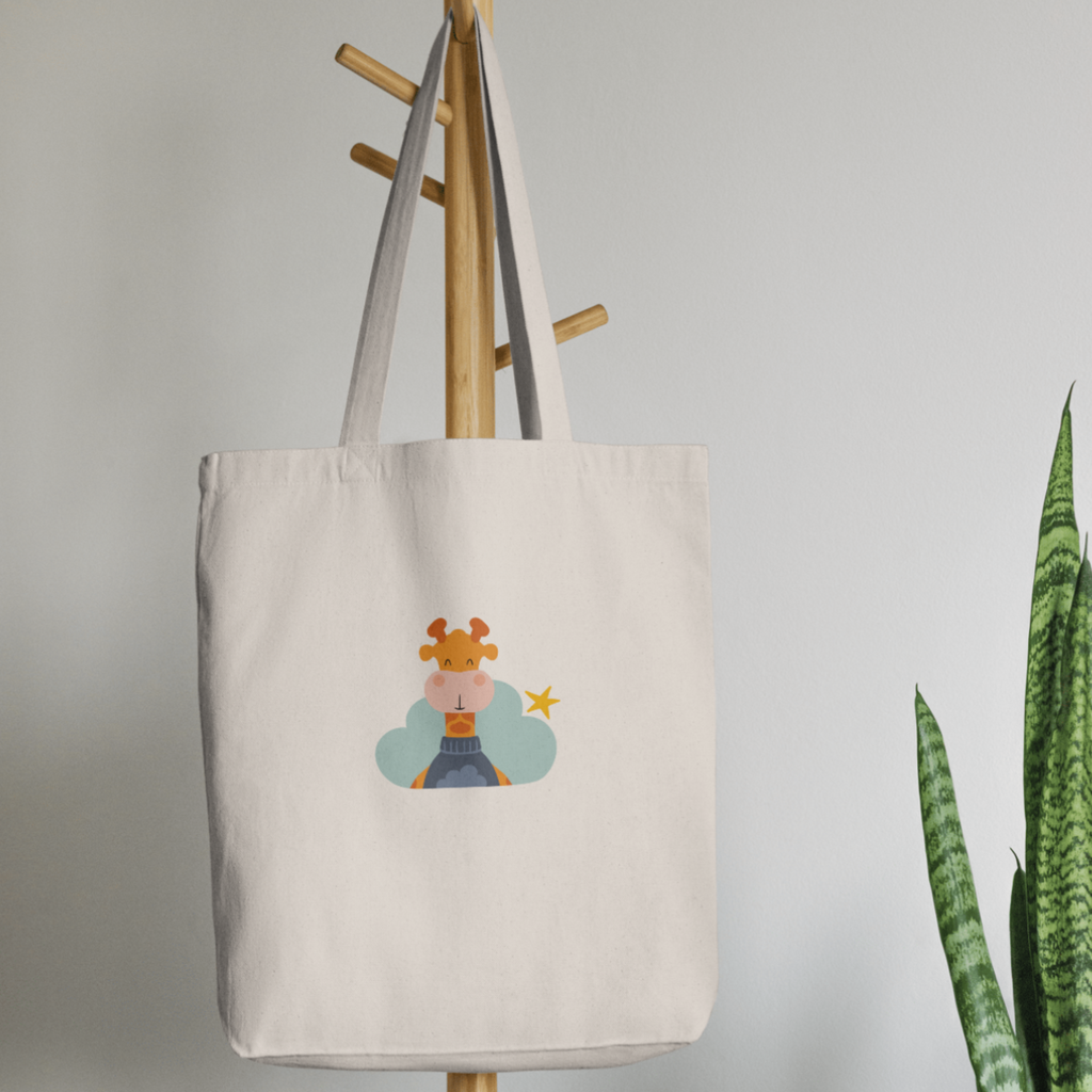 Bolsa Tote Bag color beige en  perchero, mostrando el estampado de la jirafa Lazaro en una Nube color verde y una estrella amarilla
