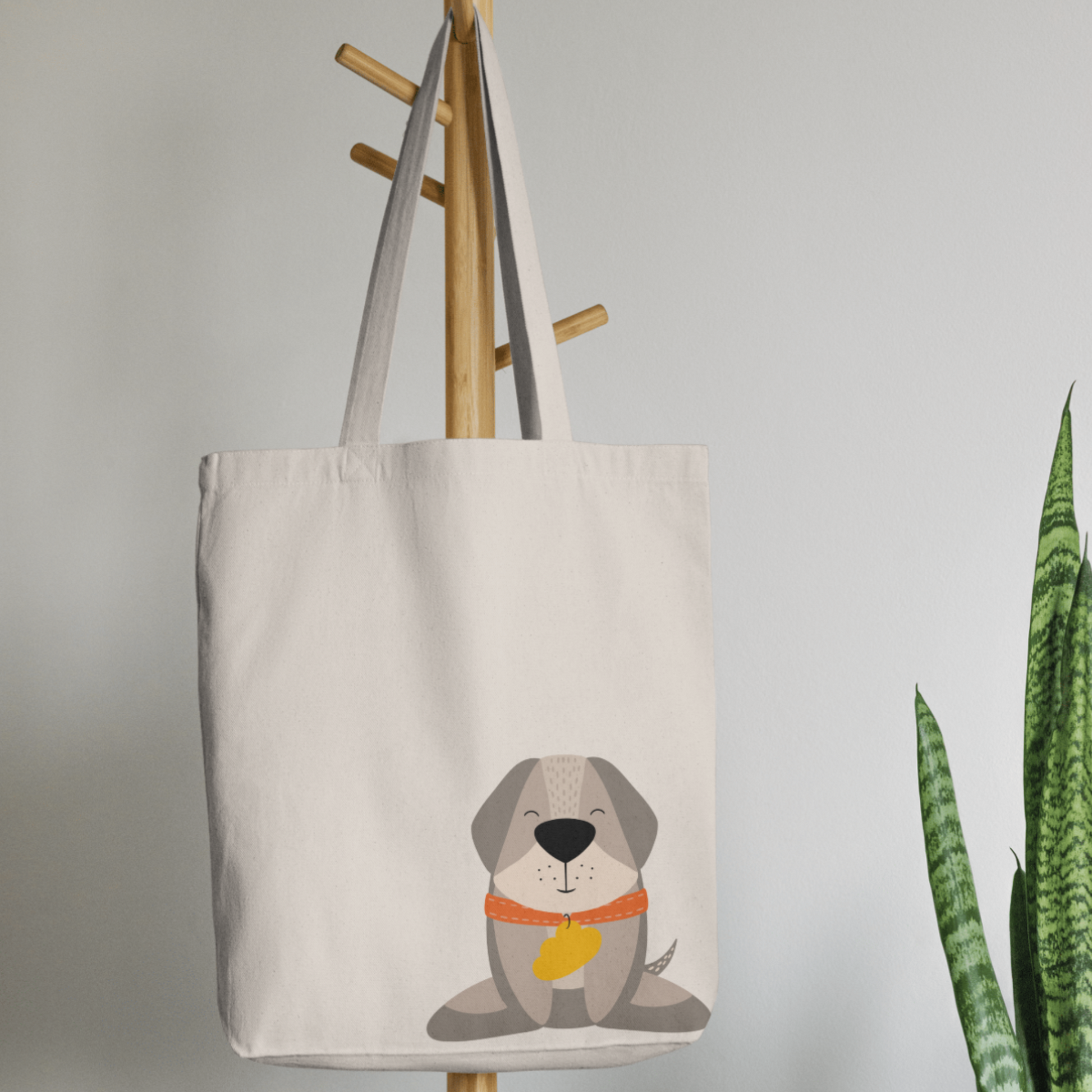 Bolsa Tote Bag color beige en  perchero, mostrando el estampado del perro Leandro con collar naranja y placa amarilla en forma de nube